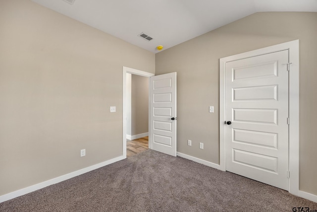 unfurnished bedroom with vaulted ceiling and carpet floors