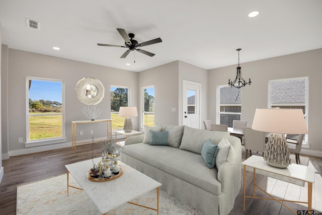 living room with ceiling fan with notable chandelier, dark hardwood / wood-style flooring, and a healthy amount of sunlight