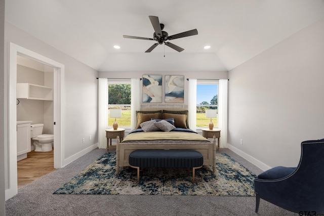 carpeted bedroom with multiple windows, vaulted ceiling, ceiling fan, and ensuite bathroom