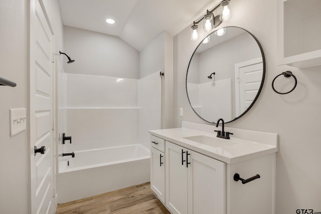 bathroom with vanity, bathtub / shower combination, lofted ceiling, and wood-type flooring