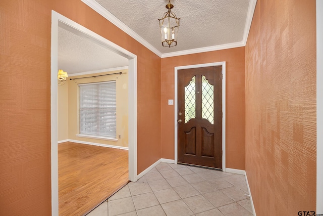 entryway with a notable chandelier, ornamental molding, a textured ceiling, and light tile patterned flooring