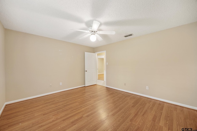 spare room with ceiling fan, a textured ceiling, and light wood-type flooring