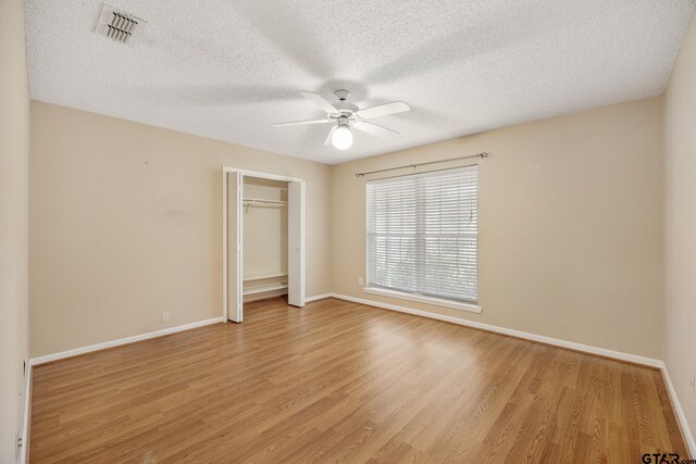 unfurnished bedroom featuring a textured ceiling, light hardwood / wood-style floors, a closet, and ceiling fan