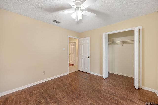 unfurnished bedroom featuring dark wood-type flooring, ceiling fan, a closet, and a textured ceiling