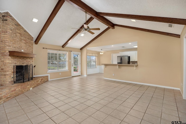 unfurnished living room with vaulted ceiling with beams, a textured ceiling, light tile patterned floors, ceiling fan, and a fireplace