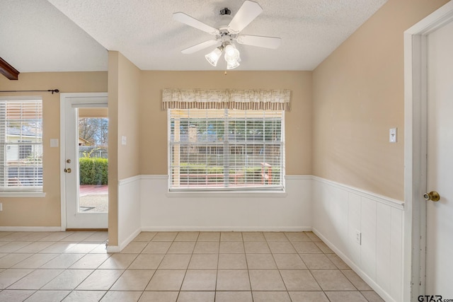 spare room with light tile patterned floors, a textured ceiling, and ceiling fan