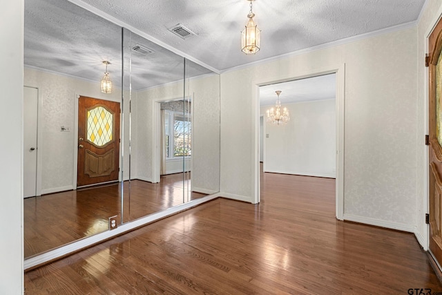 foyer featuring an inviting chandelier, ornamental molding, dark hardwood / wood-style flooring, and a textured ceiling