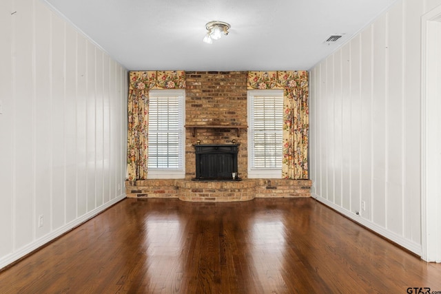 unfurnished living room with hardwood / wood-style flooring, plenty of natural light, and a brick fireplace