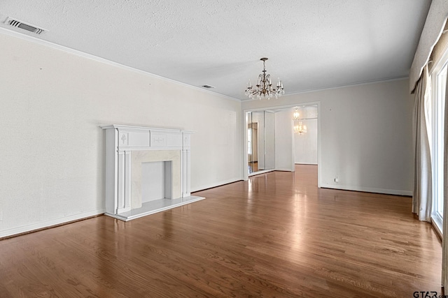 unfurnished living room featuring dark hardwood / wood-style flooring, crown molding, a textured ceiling, and a chandelier