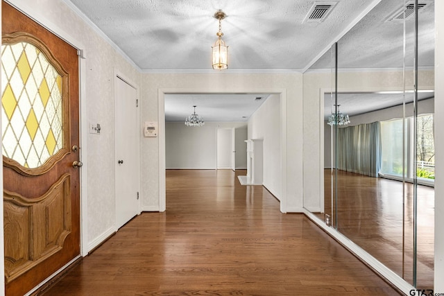 entryway with crown molding, dark hardwood / wood-style floors, a textured ceiling, and a chandelier