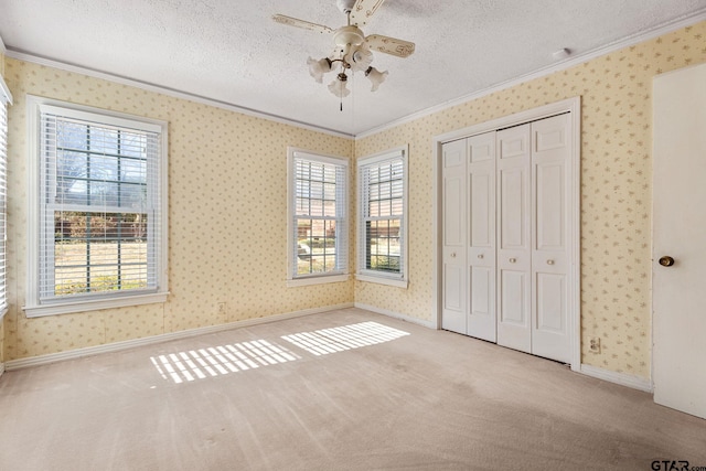 unfurnished bedroom with multiple windows, crown molding, light colored carpet, and a textured ceiling