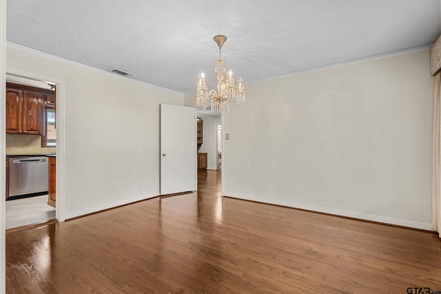 empty room with crown molding, an inviting chandelier, a textured ceiling, and light hardwood / wood-style floors