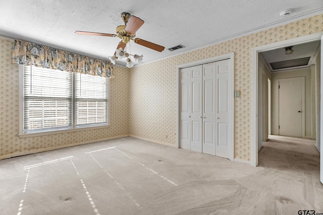 unfurnished bedroom featuring ceiling fan, light colored carpet, a closet, and a textured ceiling