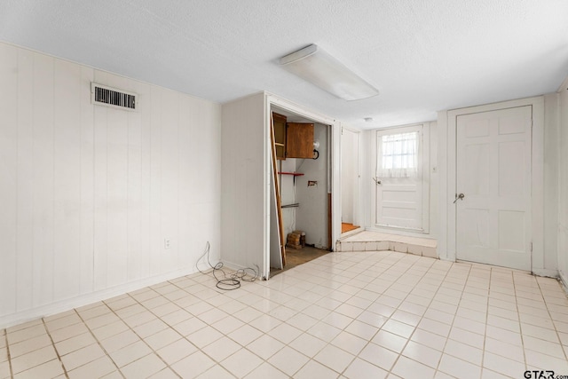 foyer entrance featuring light tile patterned floors and a textured ceiling