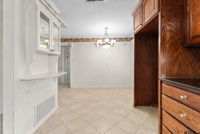 interior space with light tile patterned floors, a textured ceiling, and a notable chandelier