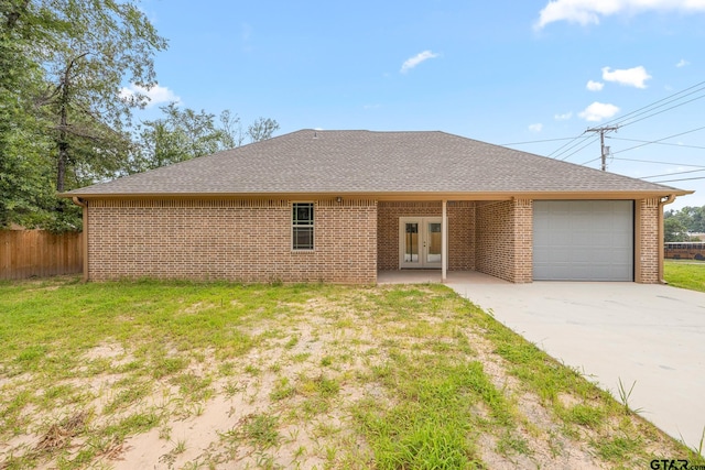 view of front of property with french doors, a garage, and a front lawn