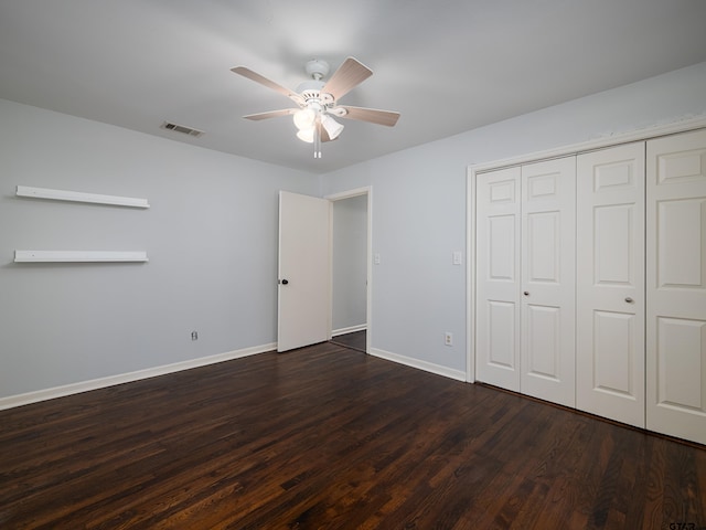 unfurnished bedroom featuring dark wood-type flooring, a closet, and ceiling fan