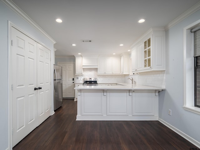 kitchen with stainless steel appliances, white cabinetry, kitchen peninsula, dark hardwood / wood-style floors, and crown molding