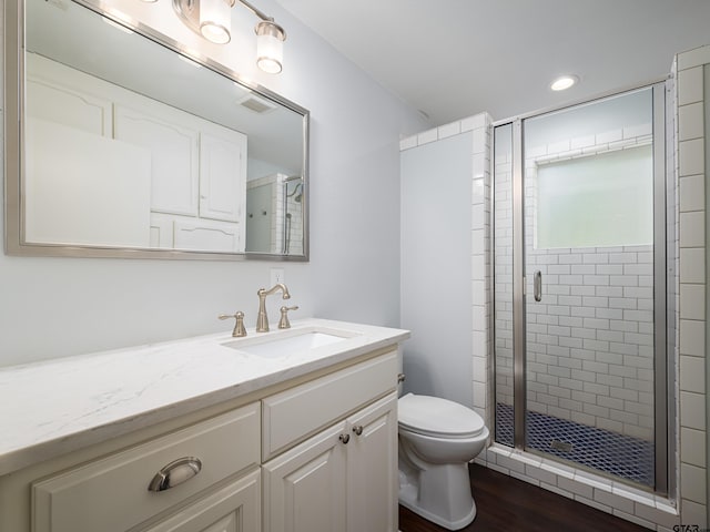 bathroom with toilet, vanity, hardwood / wood-style flooring, and walk in shower