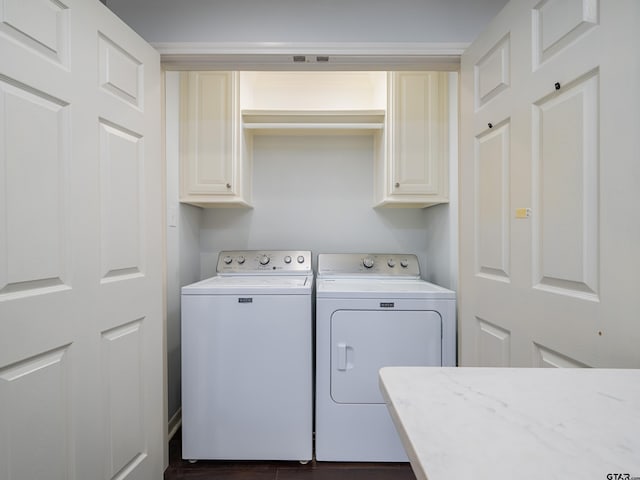 washroom with dark wood-type flooring, cabinets, and washing machine and clothes dryer