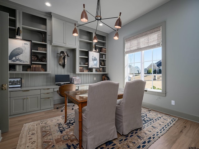 dining room with light wood finished floors, baseboards, built in desk, and recessed lighting