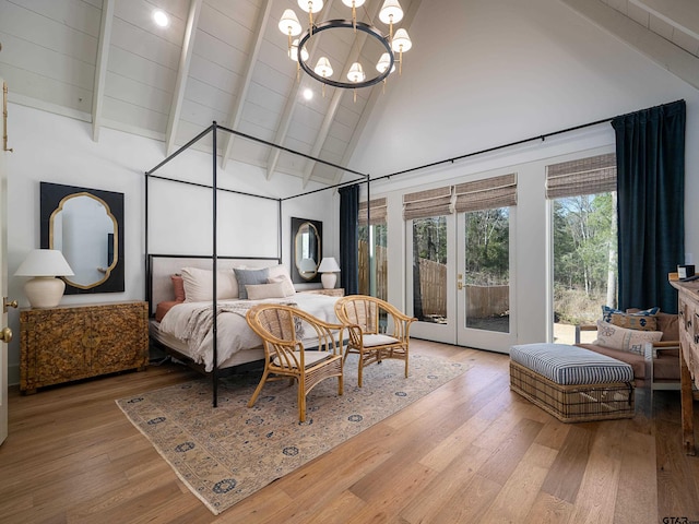 bedroom with wood finished floors, access to outside, french doors, high vaulted ceiling, and a notable chandelier