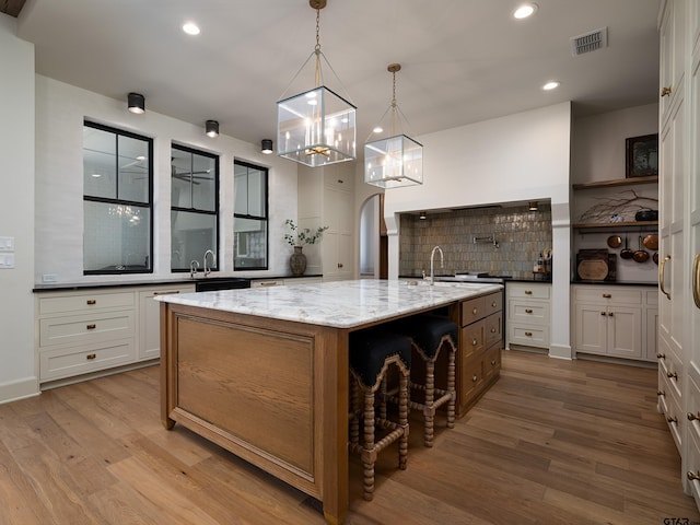 kitchen with arched walkways, a large island, decorative backsplash, white cabinets, and wood finished floors