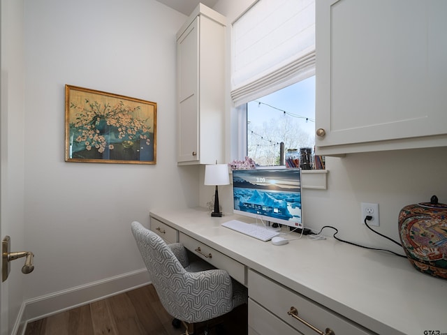 home office with dark wood-type flooring, built in study area, and baseboards