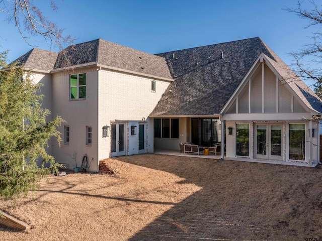 rear view of house featuring brick siding, roof with shingles, a patio area, and french doors