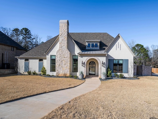 view of front of property featuring a standing seam roof, brick siding, metal roof, and roof with shingles