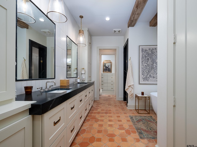 full bathroom with a freestanding bath, double vanity, beamed ceiling, and a sink