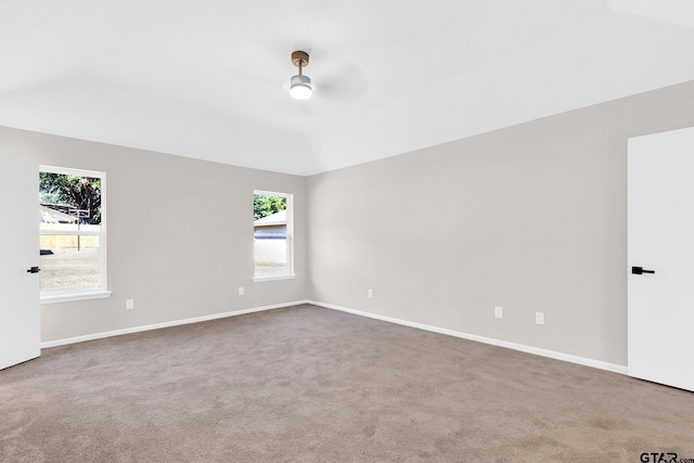 spare room featuring baseboards, vaulted ceiling, carpet floors, and a ceiling fan