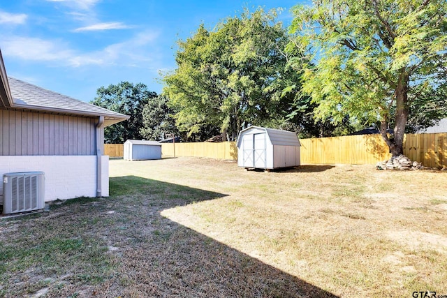 view of yard featuring a fenced backyard, central AC unit, an outbuilding, and a storage unit