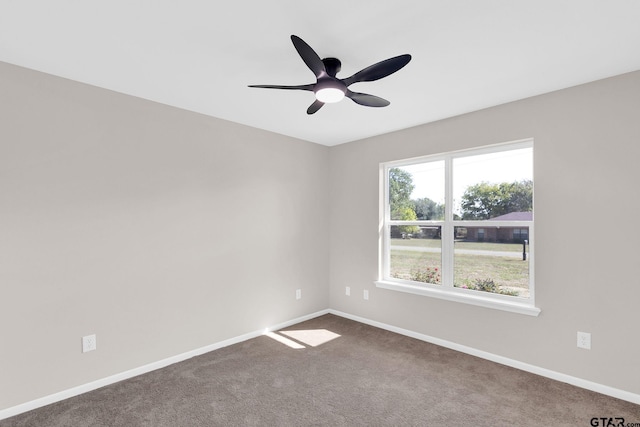 carpeted spare room featuring baseboards and a ceiling fan