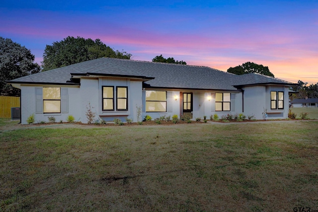view of front of home featuring a lawn and roof with shingles