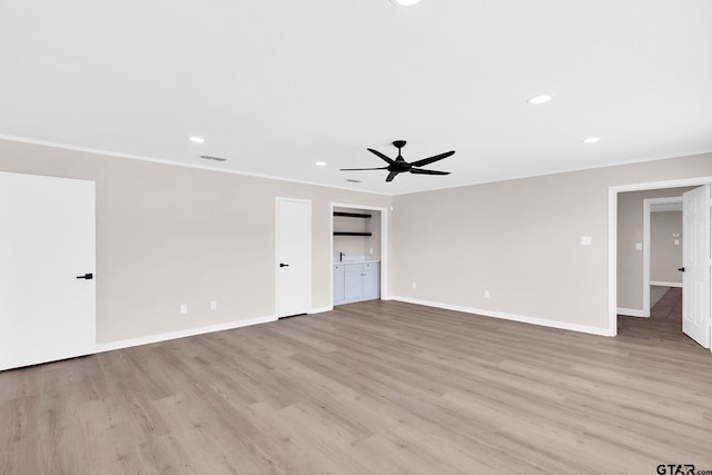interior space with light wood-style flooring, ornamental molding, baseboards, visible vents, and a ceiling fan