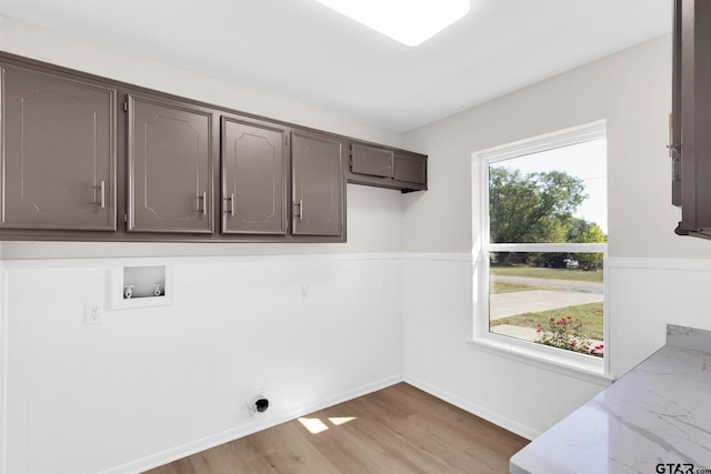 clothes washing area with light wood-type flooring, washer hookup, cabinet space, electric dryer hookup, and wainscoting