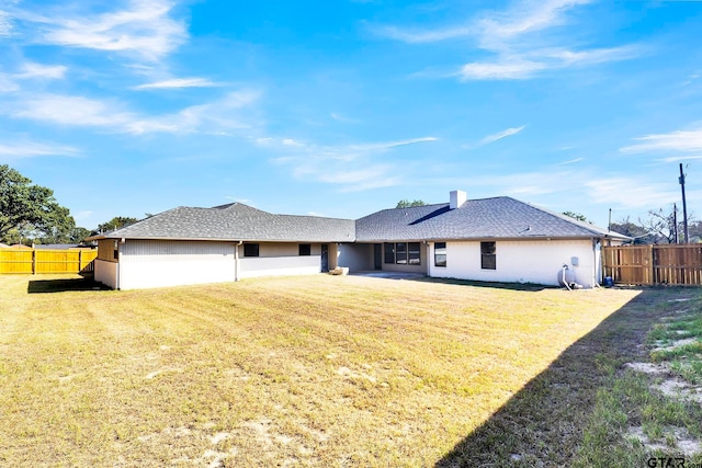 view of front facade with a front yard, a shingled roof, and fence