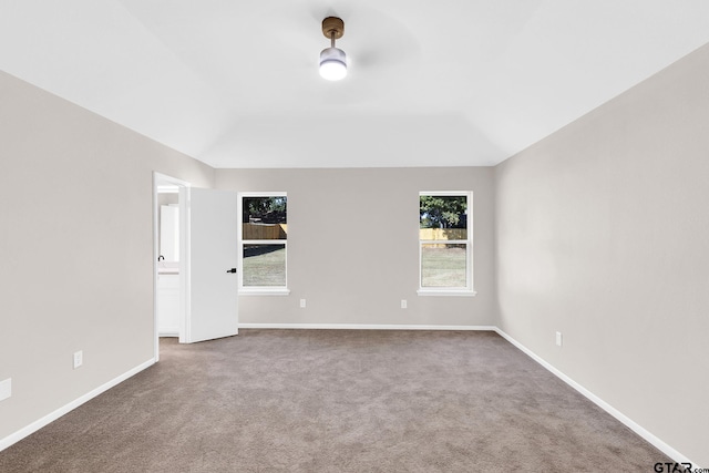 spare room with carpet flooring, baseboards, and vaulted ceiling