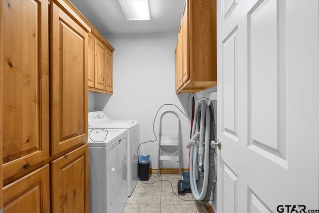 washroom featuring light tile patterned floors, cabinets, and washing machine and clothes dryer