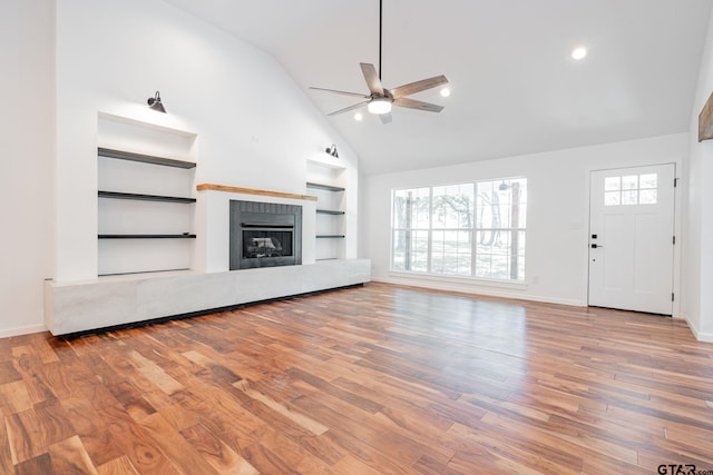 unfurnished living room featuring built in features, plenty of natural light, hardwood / wood-style flooring, and ceiling fan