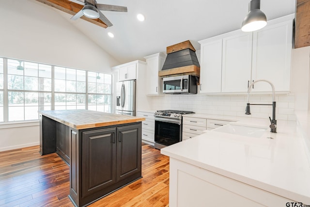 kitchen with pendant lighting, appliances with stainless steel finishes, sink, tasteful backsplash, and white cabinetry