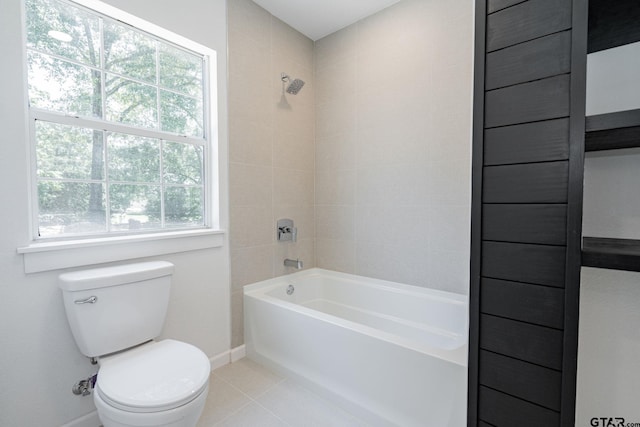 bathroom with toilet, tiled shower / bath, tile patterned floors, and a wealth of natural light