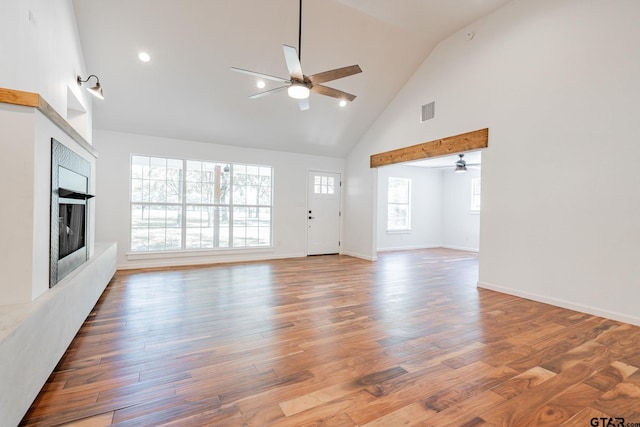 unfurnished living room with ceiling fan, high vaulted ceiling, and hardwood / wood-style flooring