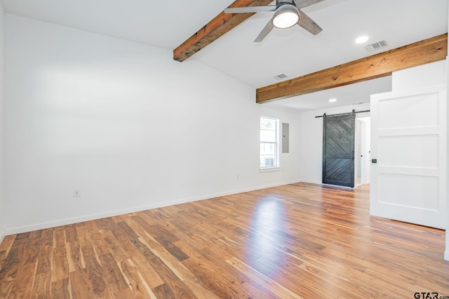 spare room featuring electric panel, beamed ceiling, a barn door, and light hardwood / wood-style flooring