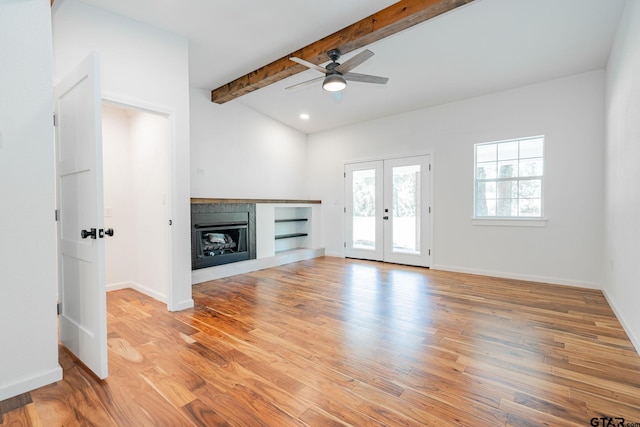 unfurnished living room featuring ceiling fan, french doors, vaulted ceiling with beams, and light hardwood / wood-style floors