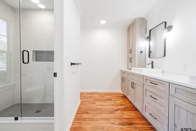 bathroom with vanity, a shower with shower door, ornamental molding, and wood-type flooring