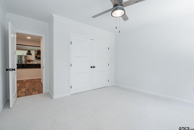 unfurnished bedroom with ceiling fan, light carpet, a closet, and ornamental molding