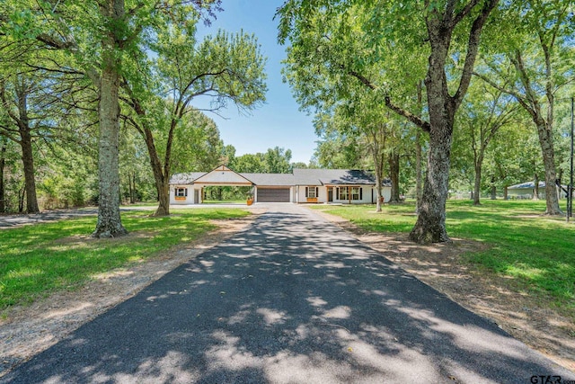 ranch-style home with a garage and a front lawn