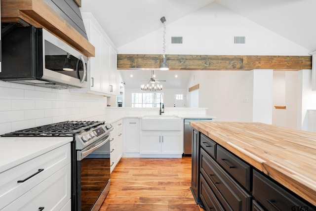 kitchen featuring decorative light fixtures, white cabinets, decorative backsplash, and stainless steel appliances